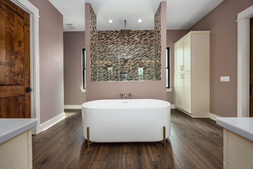Bathroom remodel in High Springs, Florida with freestanding tub, glass shower, accent tile, storage cabinet, wood flooring, and updated lighting